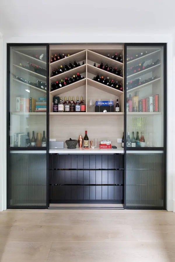 Home bar with chevron wine racks, steel-framed glass sliding doors and black drawers