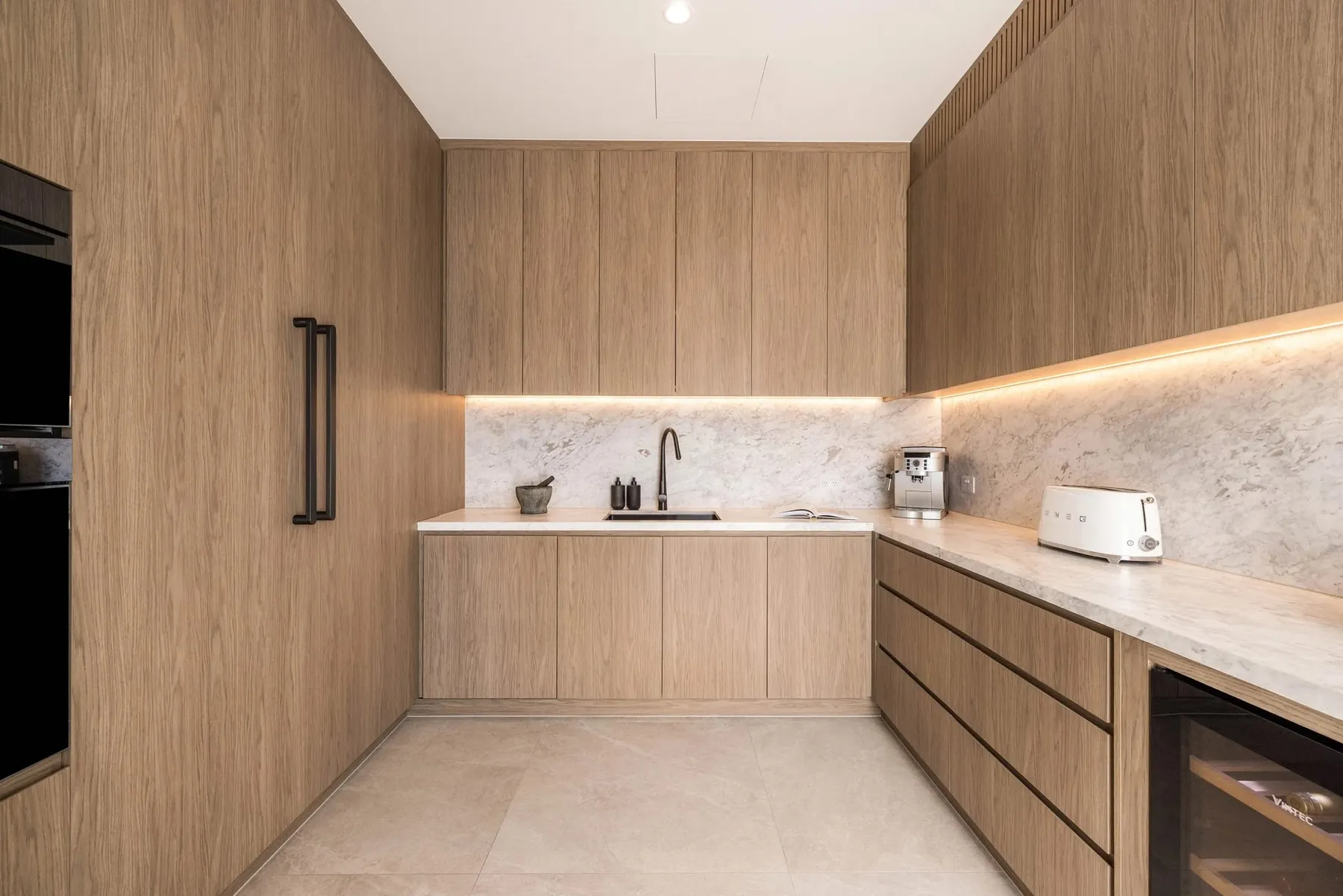 Timber-veneer butler's pantry with stone benchtop and LED strip lighting